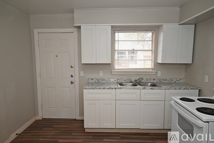 A kitchen with white cabinets and a marble countertop.