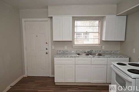 A kitchen with white cabinets and a marble countertop.