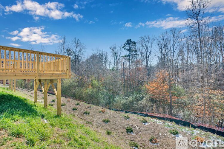 A wooden deck overlooks a forest with trees in autumn colors.