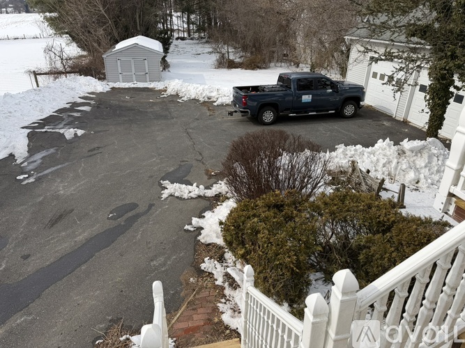A truck is parked in a driveway with snow on the ground.