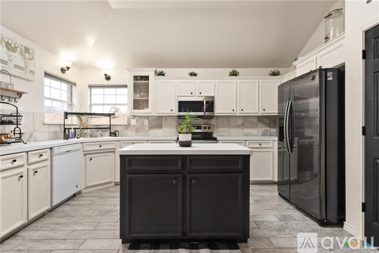 A kitchen with black and white cabinets and appliances.