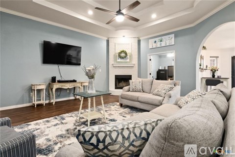 A living room with a grey couch and a television on the wall.