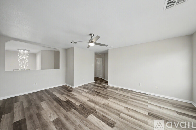 A spacious room with white marble flooring and a chandelier hanging from the ceiling.