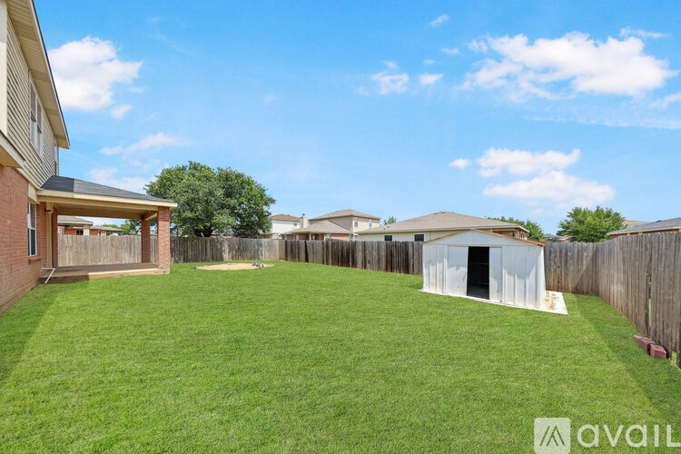 A house with a brown and beige exterior is surrounded by a fence and has a grassy yard.
