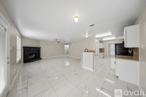 A spacious kitchen with white cabinets and a marble floor.