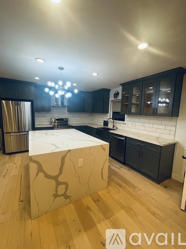 A kitchen with a marble island and wooden floors.