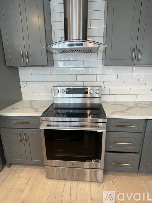 A modern kitchen with a stainless steel oven and grey cabinets.