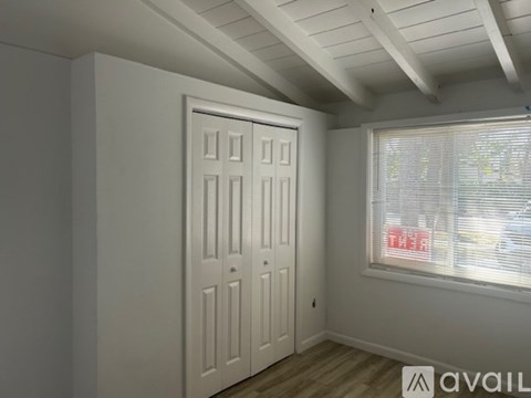 A white door in a room with a window showing a red car outside.