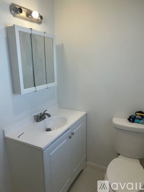 A white bathroom with a toilet, sink, and mirror.