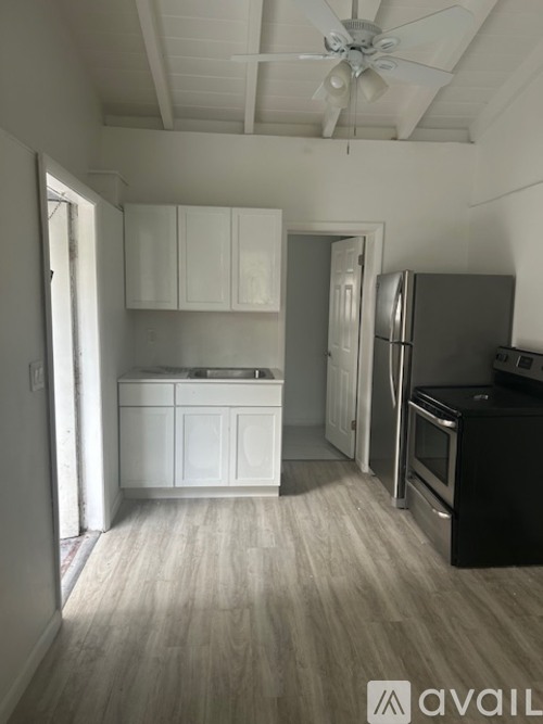 A kitchen with white cabinets and a black refrigerator.