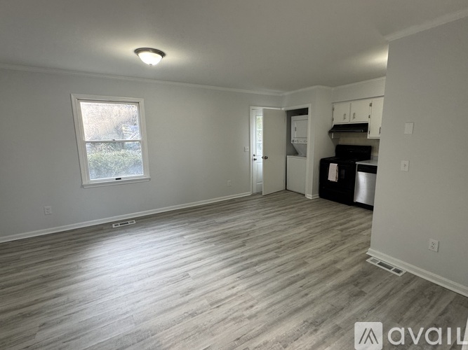 A spacious room with wood flooring and a window.