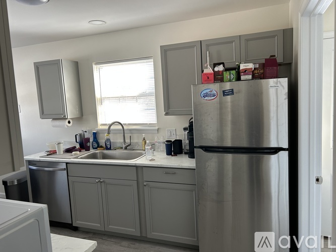 A kitchen with a stainless steel refrigerator and grey cabinets.