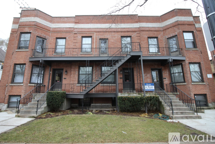 A red brick building with a black staircase in front.