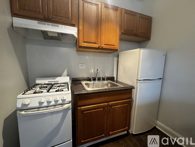 A kitchen with a white gas stove, a white refrigerator, and wooden cabinets.