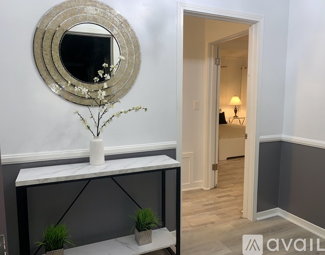 A round mirror with a flower vase on a console table.