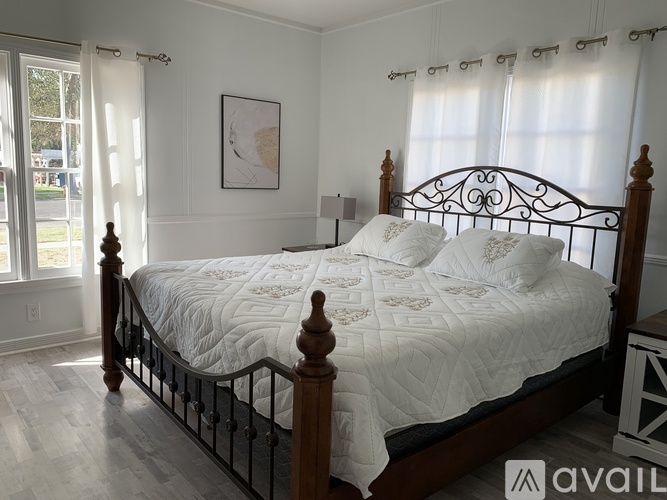 A bedroom with a large bed, two lamps, and two paintings on the wall.