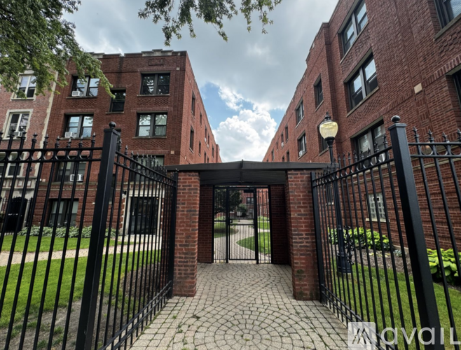 A black metal gate leads to a brick building.