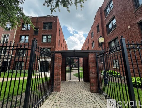 A black metal gate leads to a brick building.