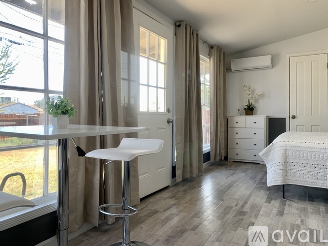 A bedroom with a white bed, a white chair, and a white table.