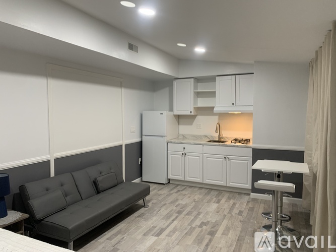 A modern living room with a grey sofa and a kitchen area in the background.