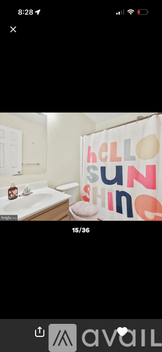 A bathroom with a shower curtain that says "Hello Sunshine".
