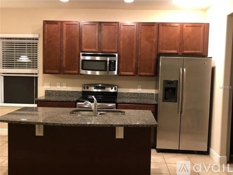 A kitchen with brown cabinets and a granite countertop.