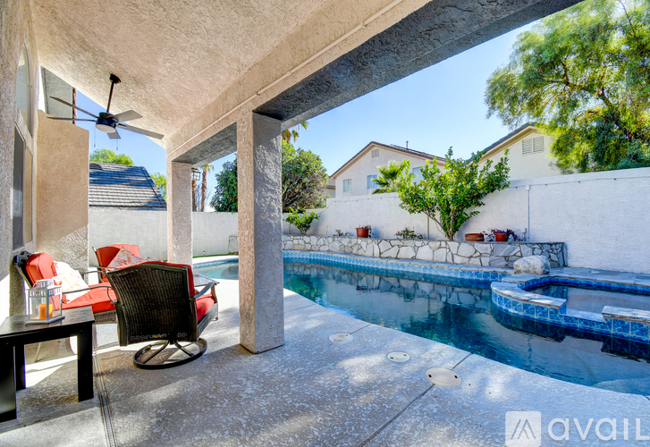 A patio with a table and chairs overlooks a pool.