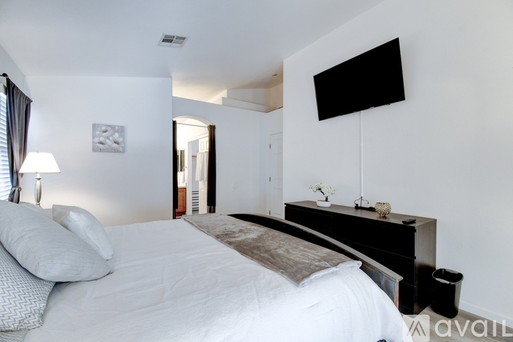 A bedroom with a large bed and a flat screen TV mounted on the wall.