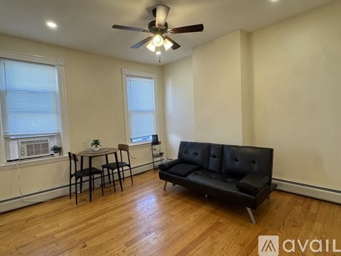 A living room with a black couch, a ceiling fan, and a dining table with chairs.