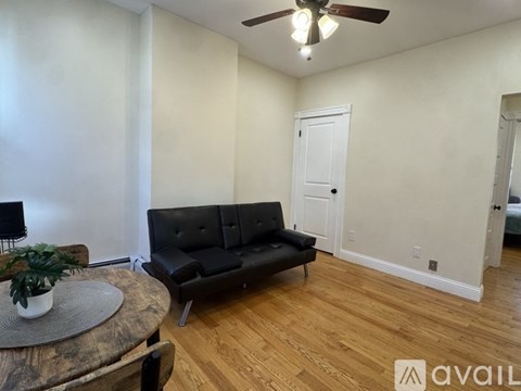 A living room with a black couch and a wooden coffee table.