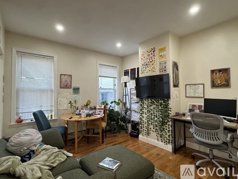 A living room with a couch, a chair, a table, a television, and a plant.