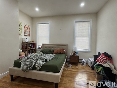 A bedroom with a bed, nightstand, and window.