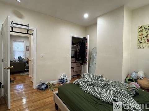 A bedroom with a bed, a closet, and a door leading to another room.