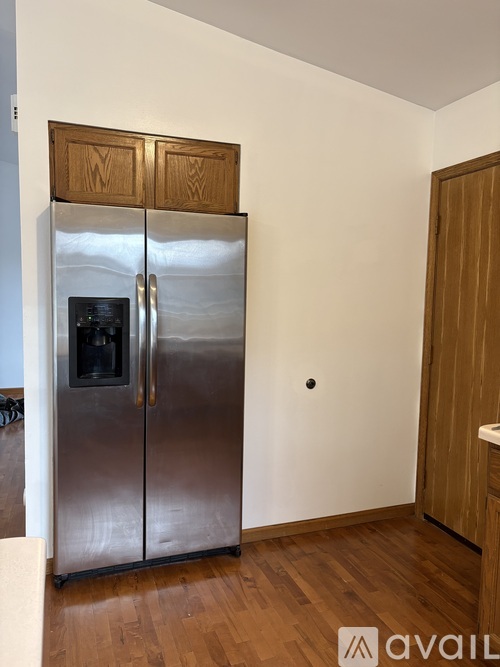 A stainless steel refrigerator with two doors is in a kitchen with wooden cabinets.