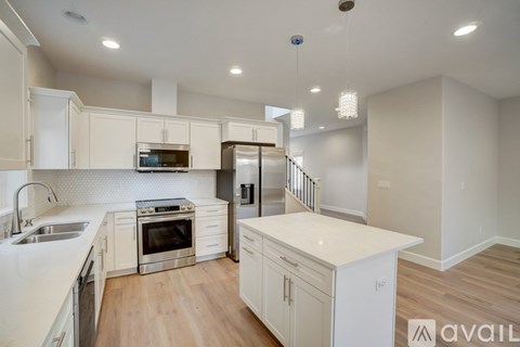 A kitchen with white cabinets and a wooden floor.