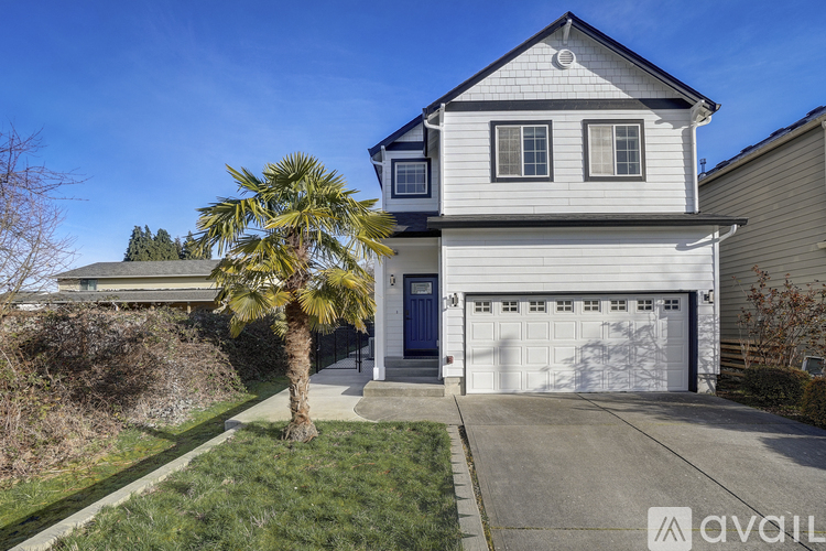 A two-story house with a garage and a palm tree in front.
