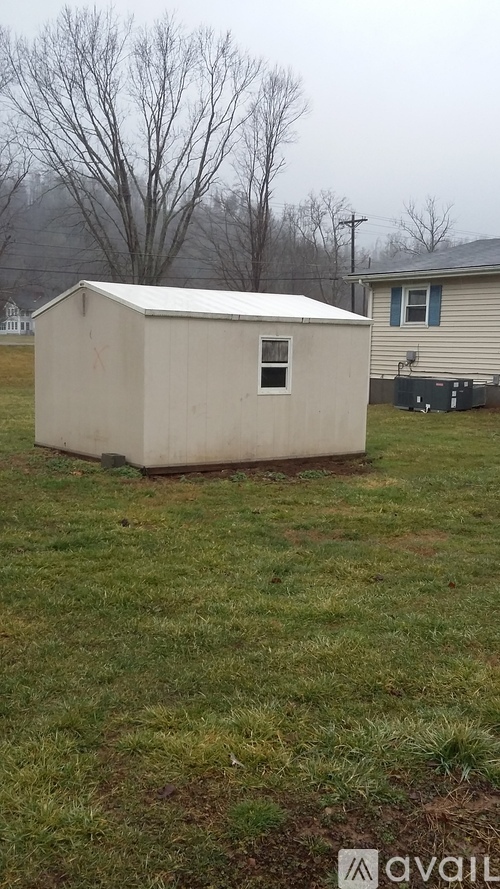 A small white shed sits in a grassy field.