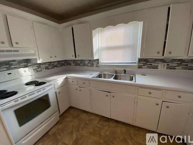 A kitchen with white cabinets and a stove top oven.