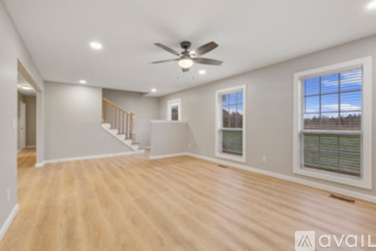 A spacious room with a ceiling fan and wooden flooring.