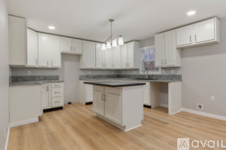 A kitchen with white cabinets and a wooden floor.
