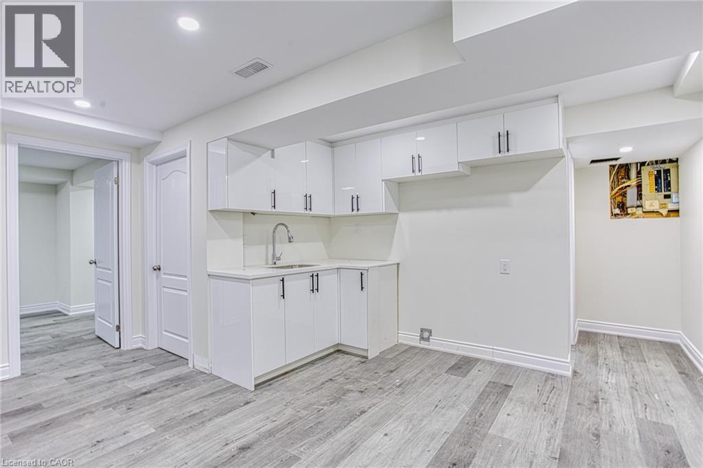 A spacious kitchen with white cabinets and a wooden floor.