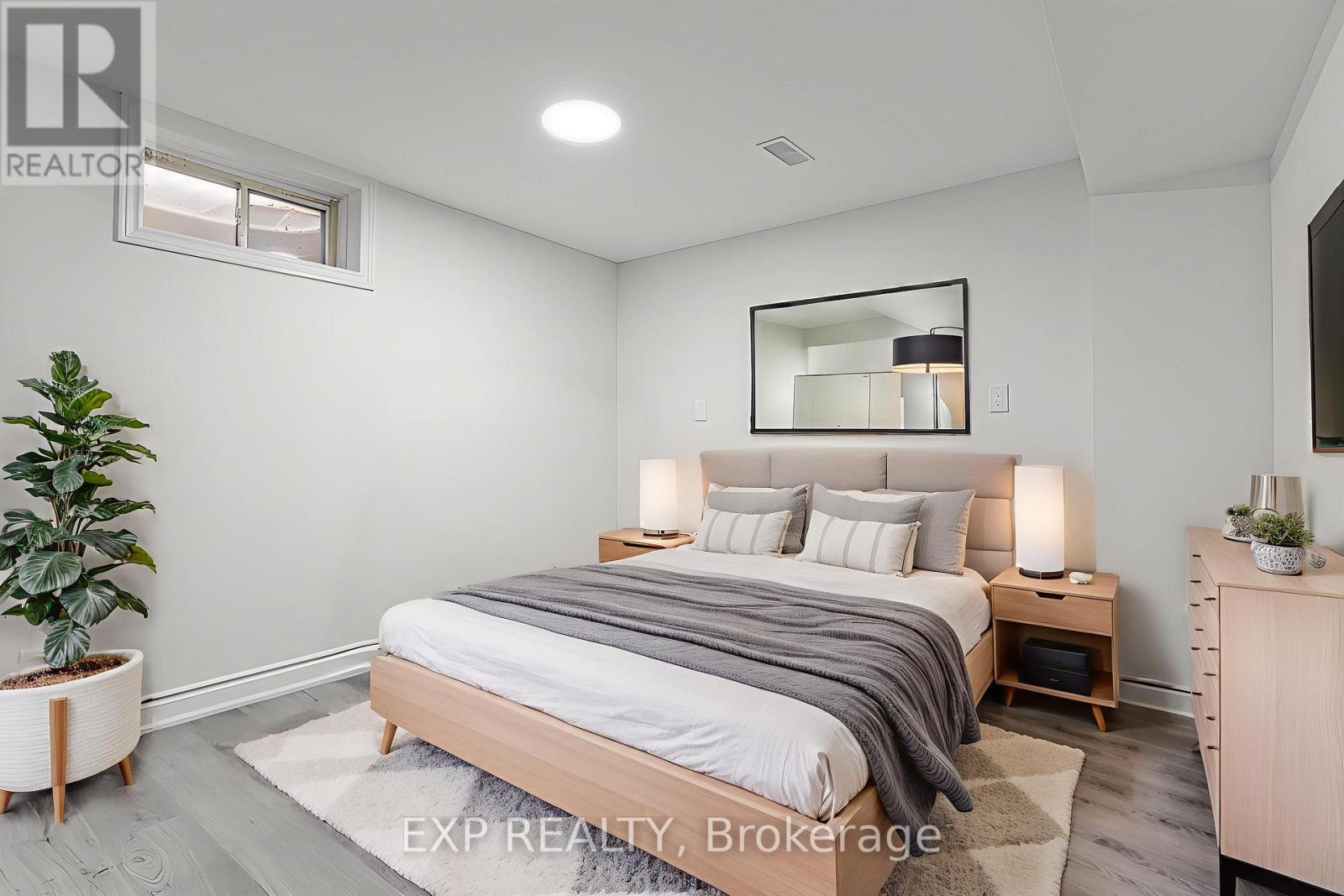 A bedroom with a bed, nightstands, and a plant.