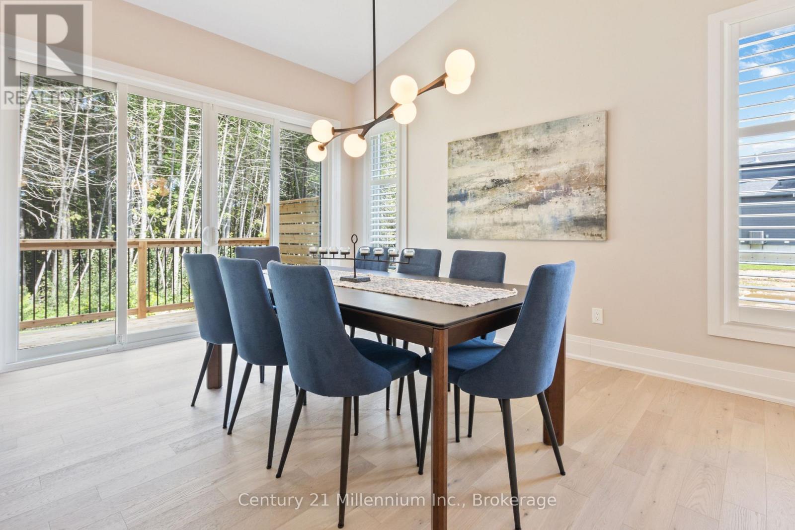 A dining room with a table and chairs and a painting on the wall.