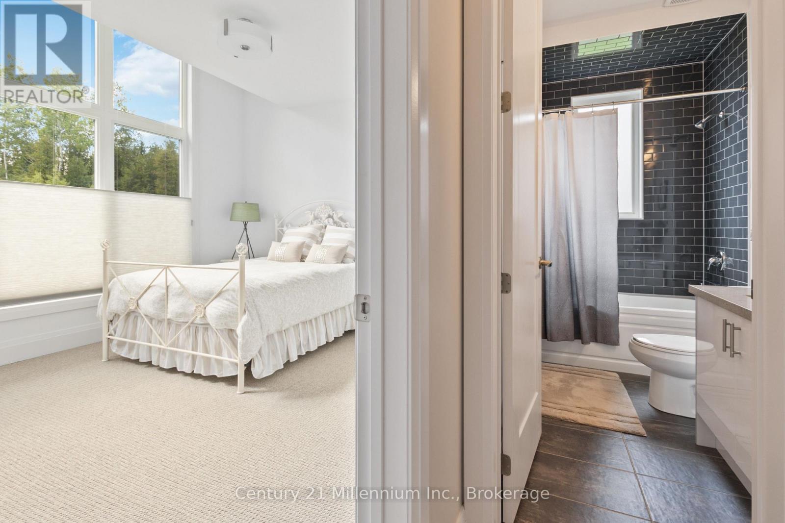 A bedroom with a white bed and a bathroom with a toilet and a shower.
