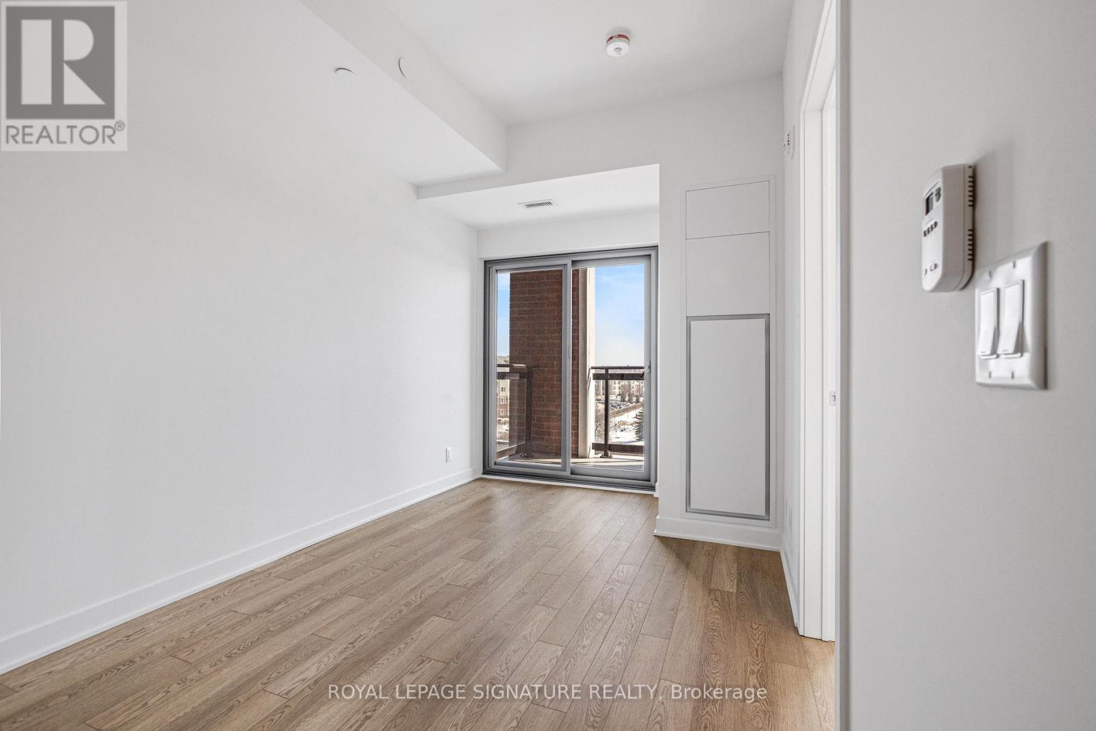 A spacious room with wooden flooring and a large window.