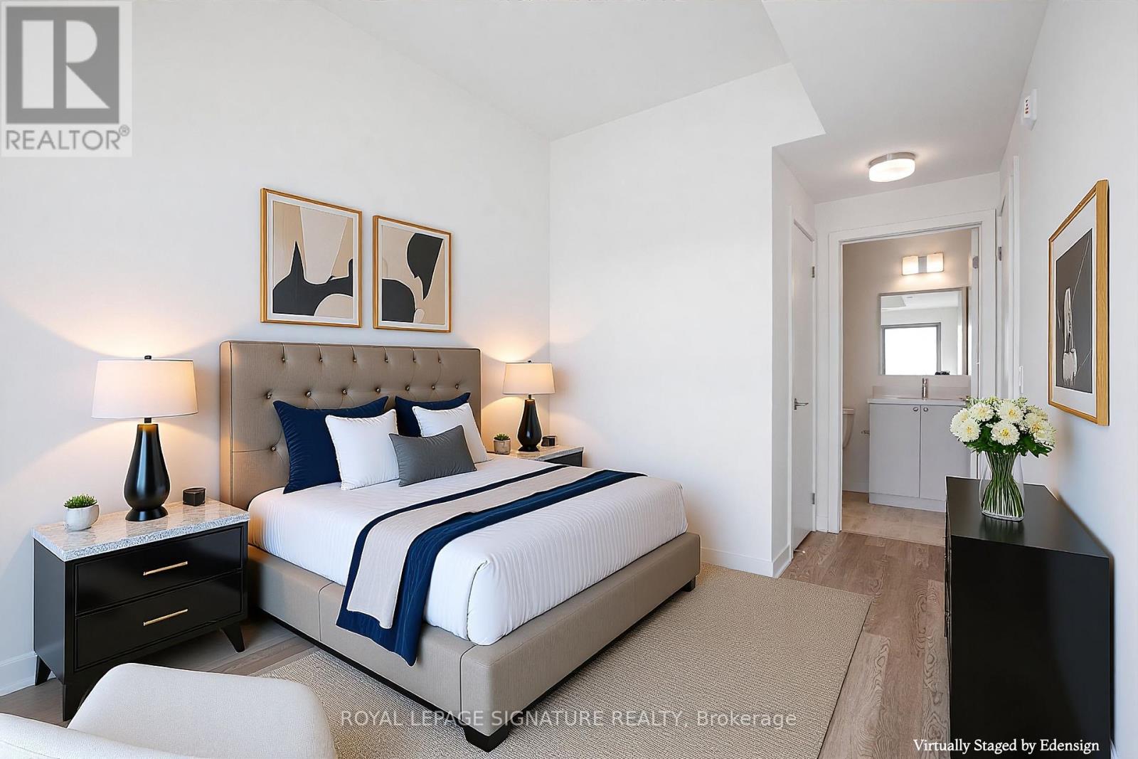 A bedroom with a large bed and a nightstand with a lamp.