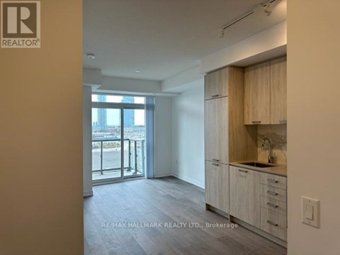 A spacious kitchen with wooden cabinets and a view of the city through the glass doors.