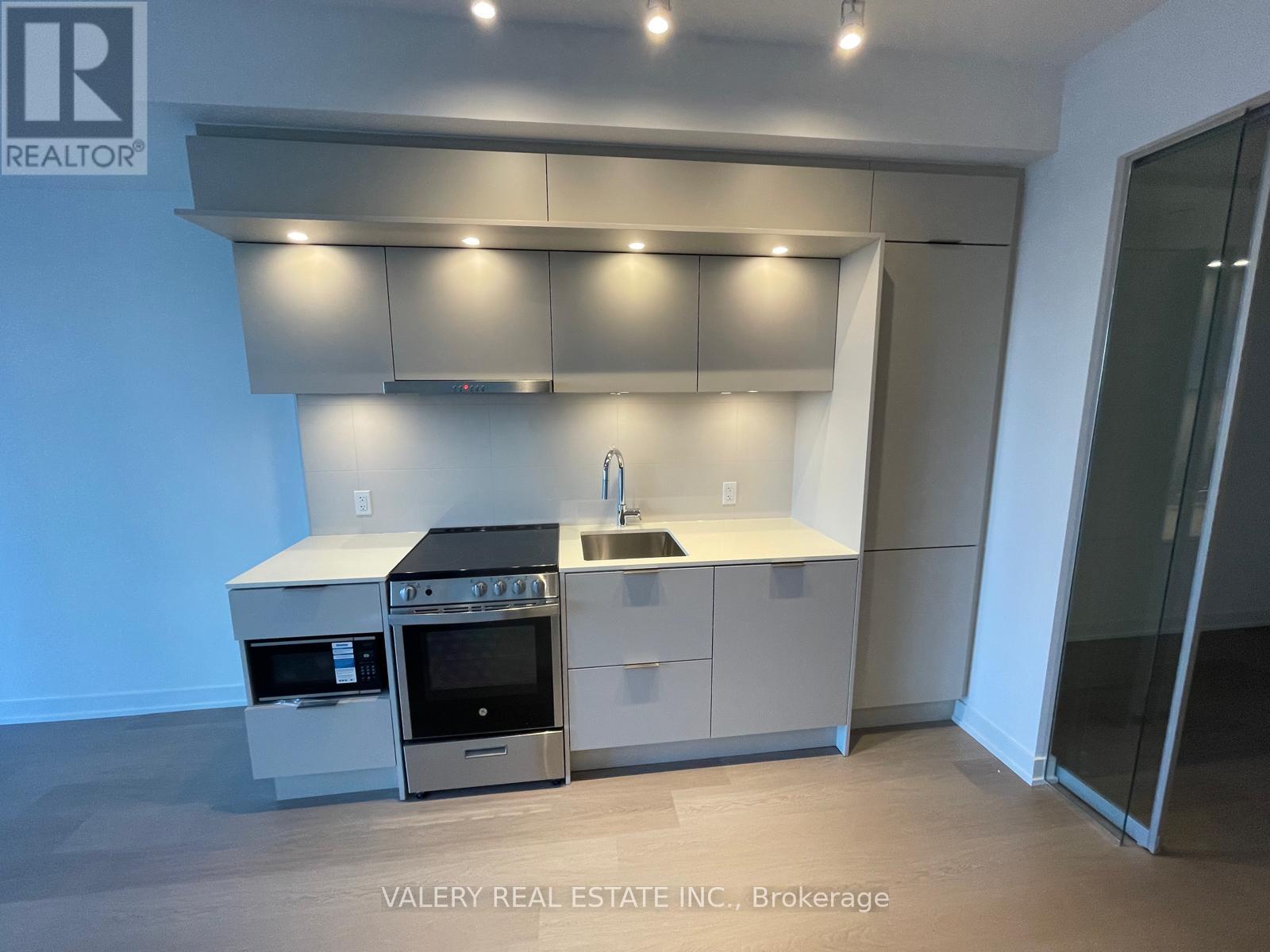 A modern kitchen with stainless steel appliances and a glass door.