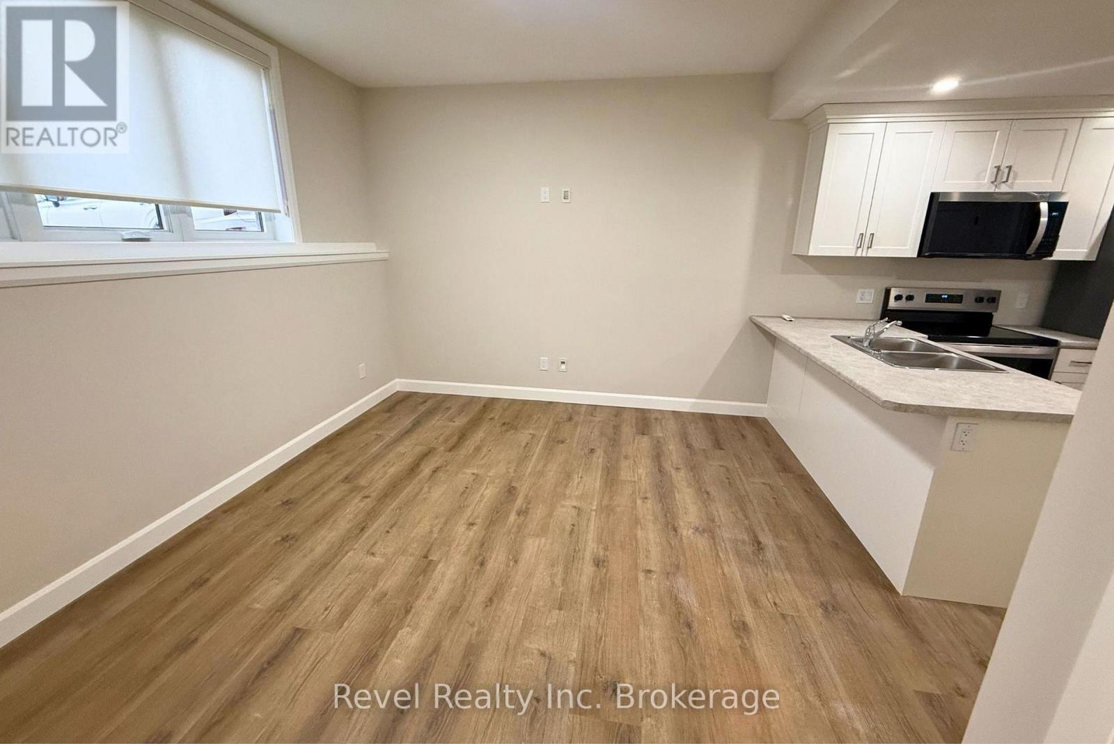 A kitchen area with wooden flooring and white walls.