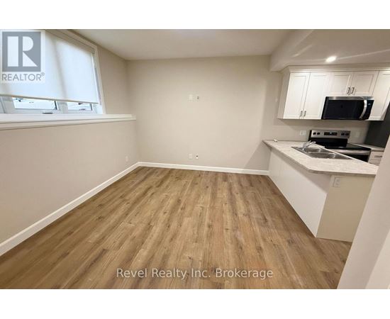 A kitchen area with wooden flooring and white walls.